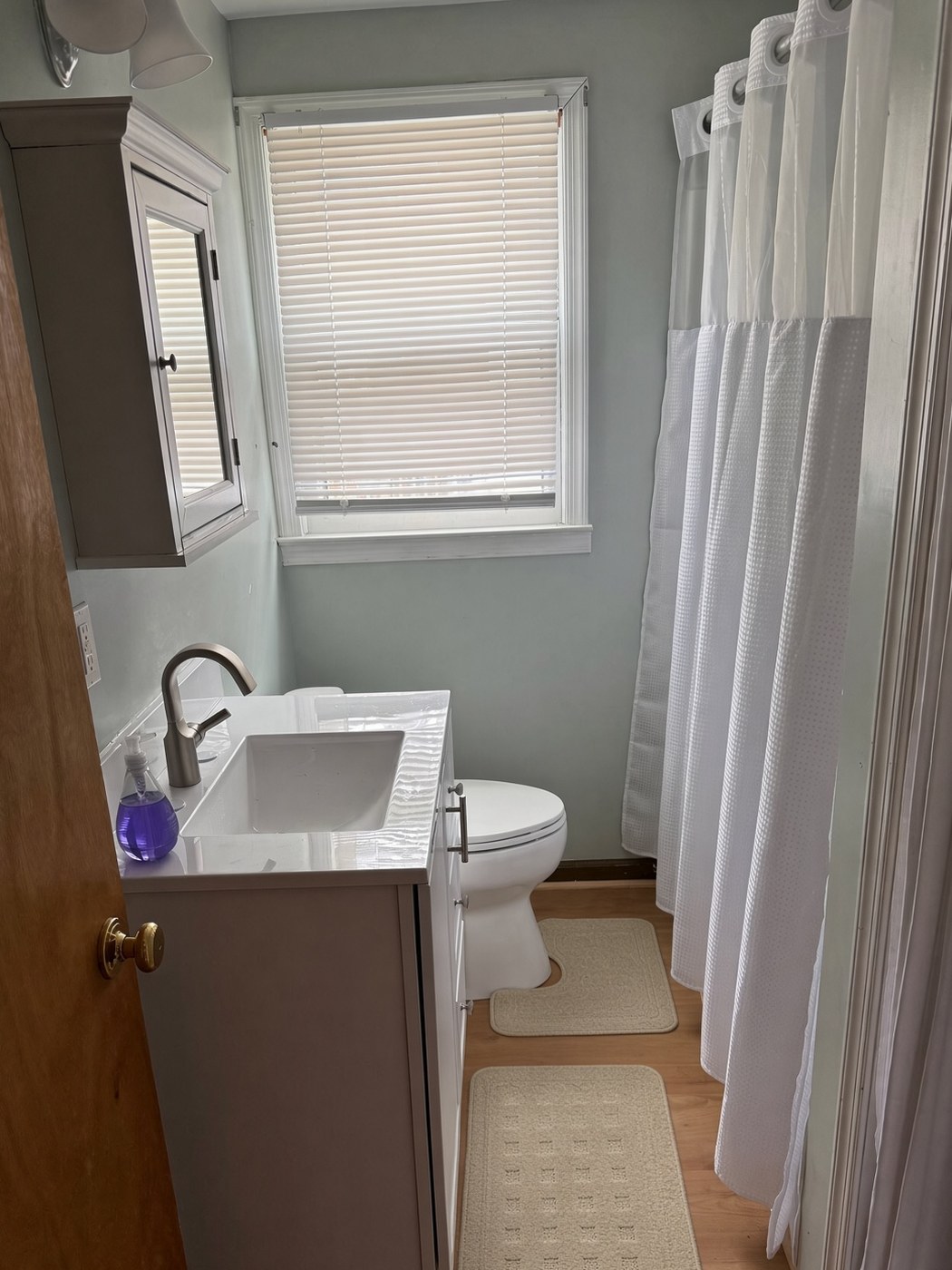 Bathroom after: white shaker vanity, new flooring and fresh paint