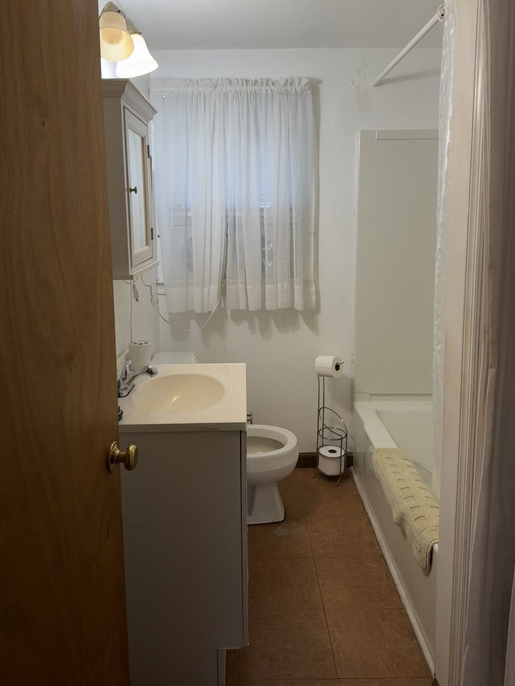 Bathroom before: dated tile floor, old vanity and fixtures