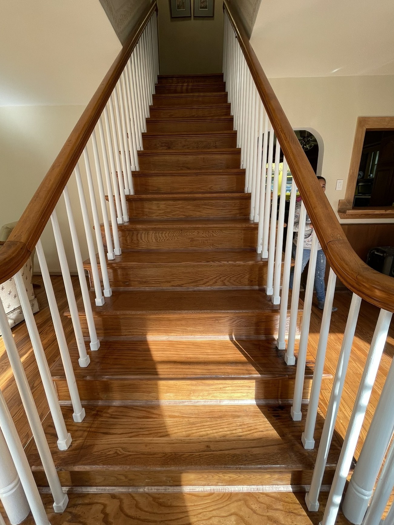 Oak staircase after refinishing: rich stain, fresh white balusters
