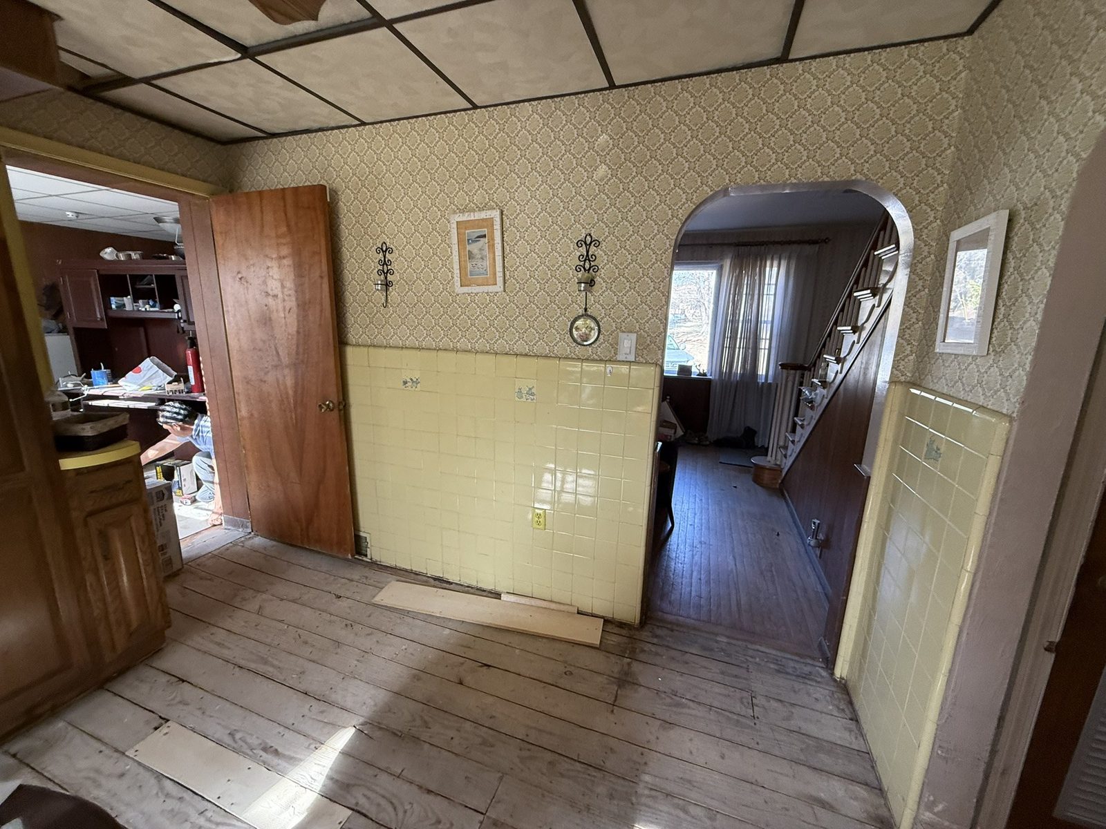 Before: closed wall with dated wallpaper and yellow tile where the breakfast bar now opens